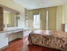 A cozy bedroom with a large bed, wooden flooring, and a well-lit dressing area.