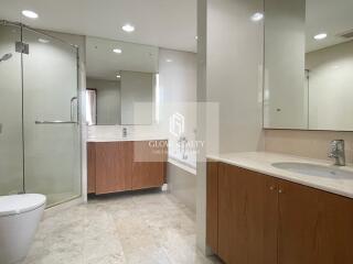 Spacious modern bathroom with glass shower and wooden cabinets