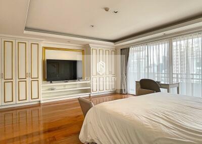 Spacious bedroom with wooden flooring and large windows