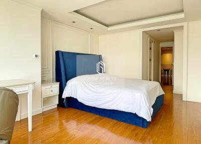 Spacious bedroom with wooden flooring and blue upholstered bed