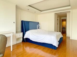 Spacious bedroom with wooden flooring and blue upholstered bed