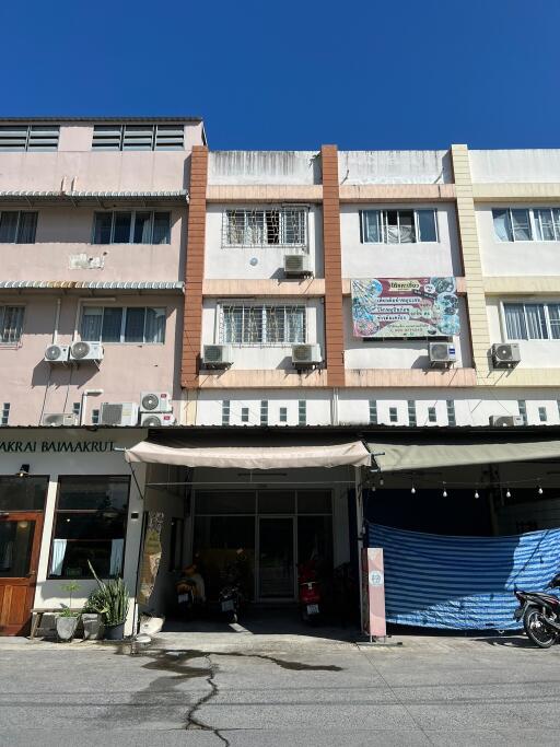 Front view of a building with retail spaces and apartments above