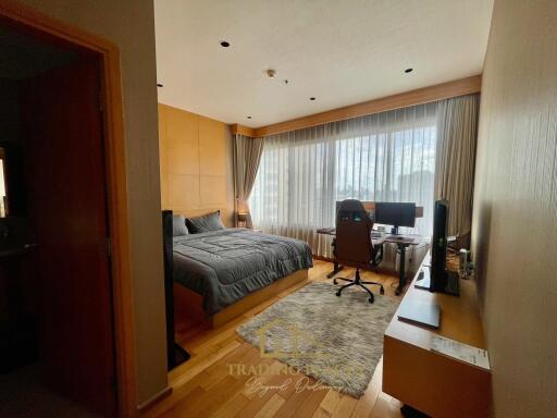 Spacious bedroom with large window, bed, desk, and storage.