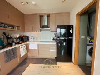 Modern kitchen with wooden cabinetry and black fridge