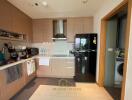 Modern kitchen with wooden cabinetry and black fridge