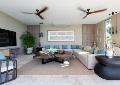 Modern living room with large wall-mounted TV, L-shaped sofa, air conditioning, and decorative elements