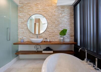 Modern bathroom with stone accent wall and round mirror