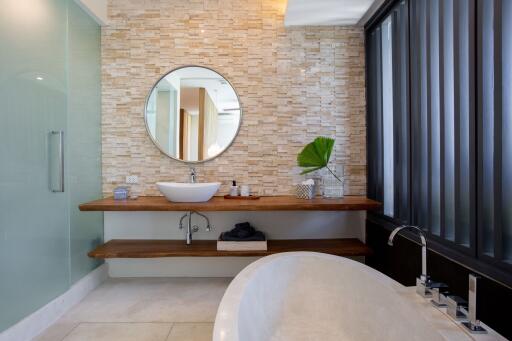 Modern bathroom with stone accent wall and round mirror