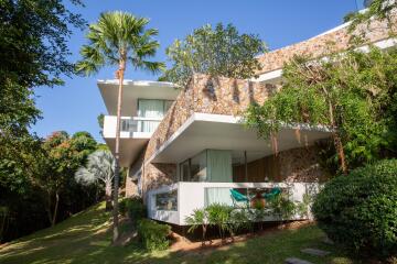 Modern multi-story building with large balconies and lush greenery