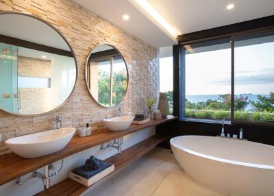 Modern bathroom with dual sinks, large mirrors, and a view