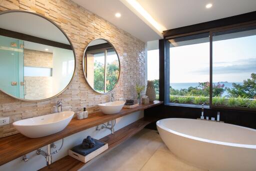 Modern bathroom with dual sinks, large mirrors, and a view