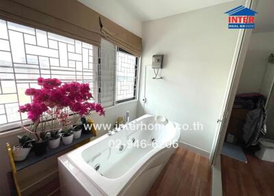 Bathroom with bathtub and potted plants by windows