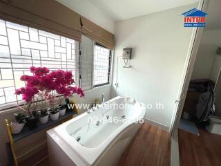 Bathroom with bathtub and potted plants by windows