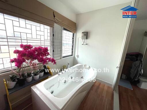 Bathroom with bathtub and potted plants by windows