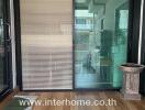 Image showing a sliding glass door entrance with a wooden floor, blinds, potted plant, and visible interior.