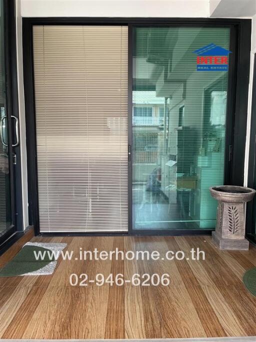 Image showing a sliding glass door entrance with a wooden floor, blinds, potted plant, and visible interior.