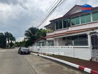 Two-story house with a gated front yard and a car parked on the street.