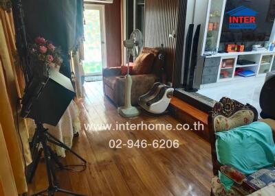 Living room with wooden flooring, armchairs, and various equipment