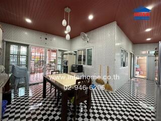 Spacious kitchen with checkered floor, white countertops, and dining table.