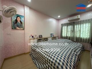 Bedroom with a double bed, checkered bedding, and pink wallpaper