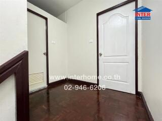 Hallway with dark wooden floor and two white doors