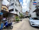 Exterior view showing multiple buildings, a car and motorbike parked in the driveway