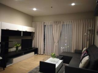 Modern living room with a black couch, white coffee table, and entertainment center