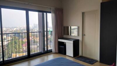 Bedroom with city view through large windows and simple furniture