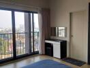 Bedroom with city view through large windows and simple furniture