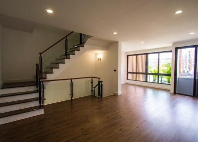 Spacious living room with a staircase, large windows, and wooden flooring