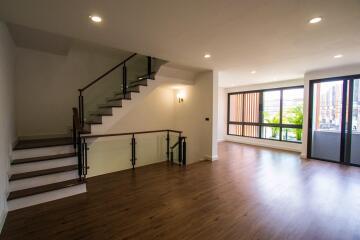 Spacious living room with a staircase, large windows, and wooden flooring