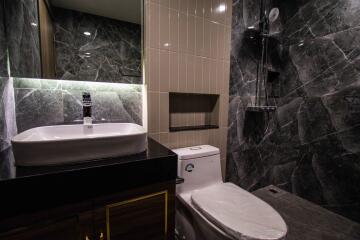 Modern bathroom with black marble tiles and standing shower