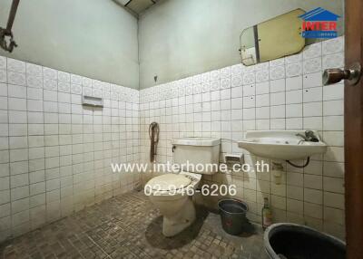 Bathroom with tiled walls, sink, toilet, and shower area