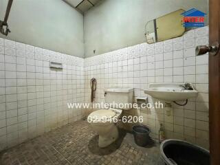 Bathroom with tiled walls, sink, toilet, and shower area