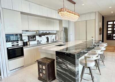 Modern kitchen with a large island, stools, chandelier, and built-in appliances