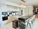 Modern kitchen with a large island, stools, chandelier, and built-in appliances