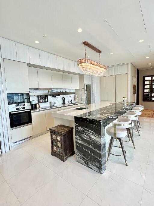 Modern kitchen with a large island, stools, chandelier, and built-in appliances