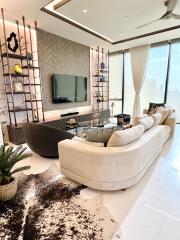 Modern living room with white couches, decorative shelves, and large windows