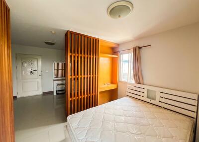 Bedroom with wooden partition, built-in shelf, and mattress