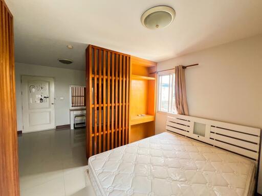 Bedroom with wooden partition, built-in shelf, and mattress