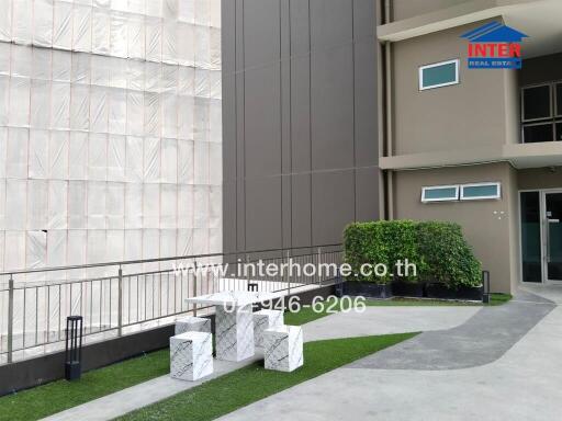 Outdoor seating area near a building with a small lawn and modern furniture