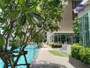 Outdoor pool area with lush greenery and modern building