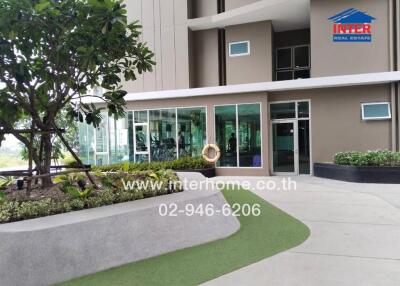 Main entrance of a modern building with greenery and large glass windows