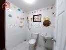 A well-lit bathroom with white tiles, toilet, sink, and wall decorations