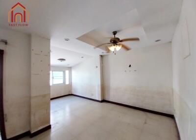 Spacious living room with large windows and ceiling fan