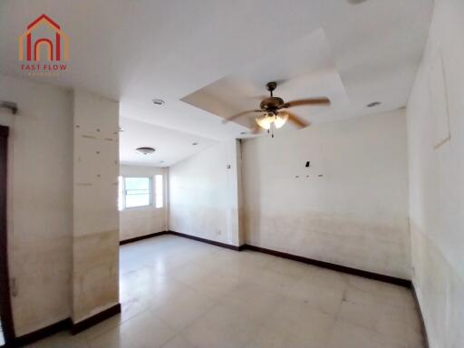 Spacious living room with large windows and ceiling fan