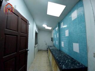 Compact kitchen with marble countertop and blue tiled wall