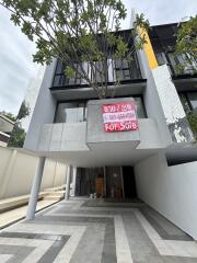 Exterior view of a modern townhouse with a for sale sign