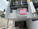 Exterior view of a modern townhouse with a for sale sign