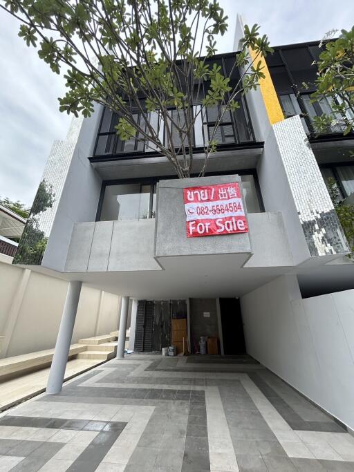 Exterior view of a modern townhouse with a for sale sign